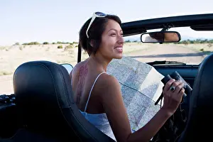 Adventure Prints: Native American woman in sun dress looking at a map in the passenger seat of a convertible