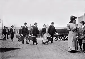 New York City Prints: New York, New York: c. 1895 Immigrants carrying their luggage as they arrivive at Ellis Island in NY harbor