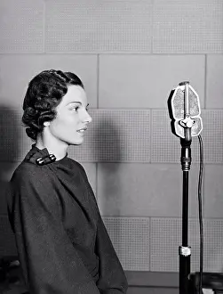 Communications Prints: New York, New York: c. 1937 A woman stands in the WOV studio in front of the microphone