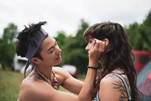 Tent Prints: non-binary asian face paints woman with curly hair at festival camp