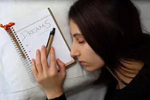 Notebook Prints: Notebook with the word Dreams written, next to a sleeping woman