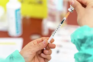 Report Prints: Nurse preparing a dose of vaccine to vaccinate against Covid