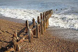 Defense Prints: Old broken and abandoned wooden groynes on shingle beach