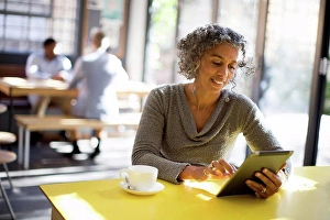 Joining Prints: Older woman using digital tablet in cafe