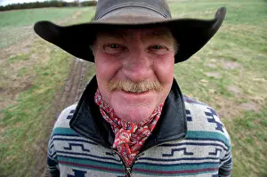 Tracks Prints: Outdoor portrait of a rancher with hat and moustache standing on his land near tire tracks; Burwell