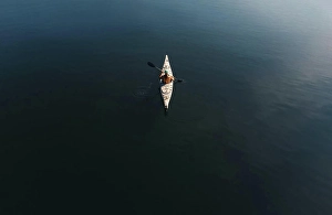 Kayak Prints: Overhead aerial view of woman paddling kayak on dark blue water