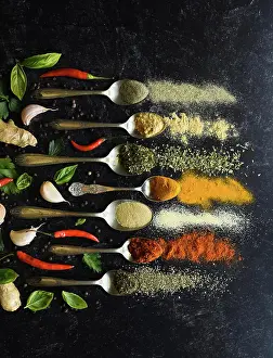 Dried Prints: Overhead of spoons full of herbs and spices on a black background