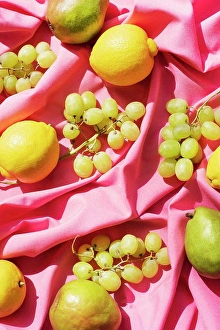 Wrinkled Prints: Overhead view of lemons, pears and grapes on pink table cloth