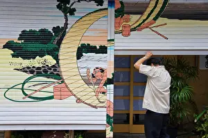 Contrast Prints: The owner opens the shutters of his traditional Japanese restaurant that are decorated with a Hokusai woodblock print
