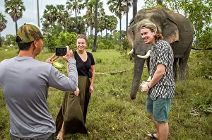 Knife Prints: A pair of western backpackers pose for a photograph next toi an Asian elephant in Phumi Khna