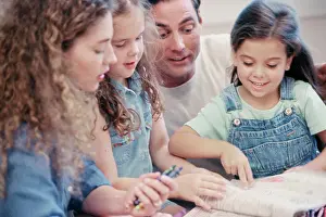 Curiosity Prints: Parents with their two daughters drawing in a coloring book