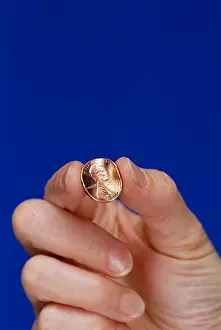 Financial Prints: Penny pincher. Hand pinching a penny
