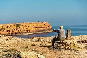 Thoughtful Prints: Pensive old man sitting on the shoreline by the sea. Traditional lord of Spanish culture