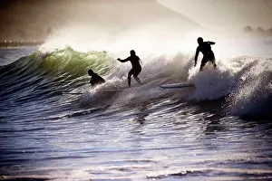 Apparel Prints: Three people surfboarding on the crest of a wave