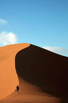 Arid Prints: Person climbing sand dune beside Deadvlei