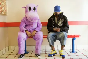 Baseball Cap Prints: Person in hippo costume sitting next to a man text messaging on a mobile phone