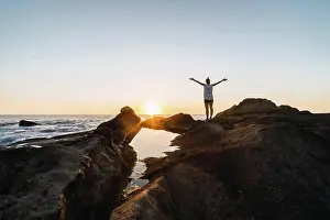 Rocks Prints: a person standing in a sea landscape against sunset