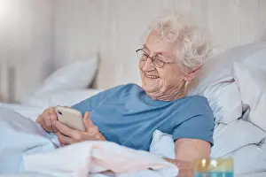 Texting Prints: Phone, bed and social media with a senior woman typing a text message while in the bedroom to relax