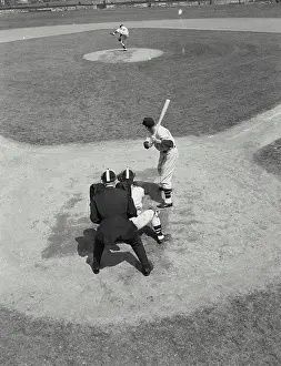 Standing On One Leg Prints: Pitcher winds up to throw a pitch to batter at home base, viewed from behind