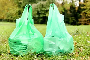 Cleaning Prints: Two full plastic bags sitting side by side on the grass filled with rubbish for recycling