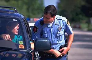 Autos Prints: Police officer approaches the driver of a car after stopping him for a traffic violation