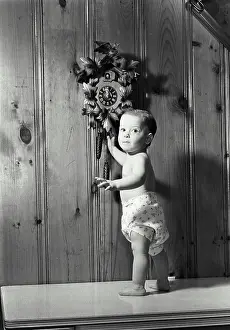 Nappy Prints: Portrait of a baby boy standing near a cuckoo clock