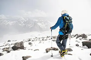 Artisan Prints: Portrait of a bearded guide with a backpack and an ice ax and sticks for Nordic walking in a hat