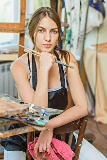 Beautiful Woman Prints: Portrait of beautiful female painter sitting on chair in studio