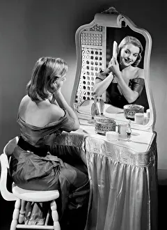 Portrait of beautiful woman combing hair in front of mirror