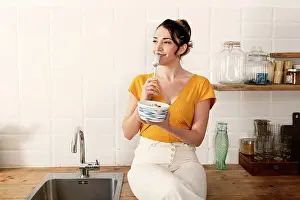 Beautiful Woman Prints: Portrait of beautiful young woman having breakfast in the kitchen