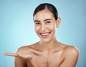 Portrait, beauty skincare and woman with product placement in studio isolated on a blue background