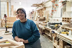 Mature Adult Prints: Portrait of a Black woman carpenter in a large woodworking shop