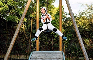 Assured Prints: Portrait of boy in astronaut costume riding on playground zip wire