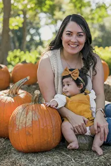 Farm Prints: Portrait of a brunette latin mom and her daughter next to a pumpkin