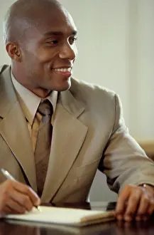 Bald Prints: Portrait of a businessman seated at an office desk writing in a notepad