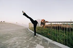 Agility Prints: Portrait carefree young female dancer doing standing splits at park railing