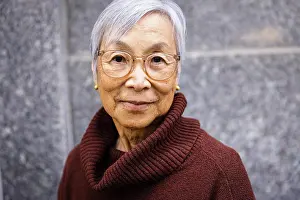 Asian And Indian Ethnicities Prints: Portrait of casual senior woman looking at camera in urban environment