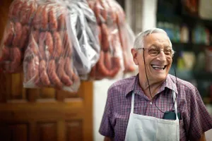 Baby Boomer Prints: Portrait of cheerful elderly butcher at work