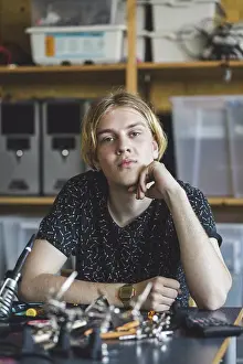 Innovation Prints: Portrait of confident young male student sitting with science project at desk in classroom at high school