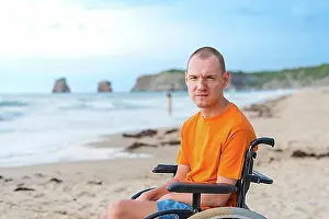 Disability Prints: Portrait a disabled person in a wheelchair on the beach enjoying nature