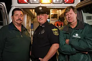 Dangerous Prints: Portrait of EMS & Police first responders standing at back of an open ambulance