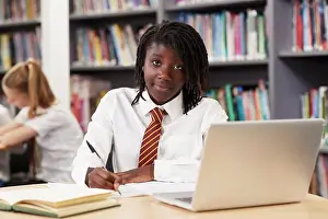 Student Prints: Portrait Of Female High School Student Wearing Uniform Working At Laptop In Library