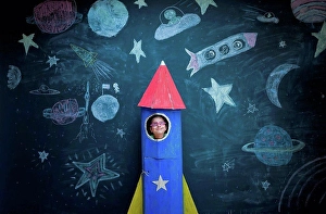 Ambitious Prints: Portrait of girl in handmade space rocket in front of space themed chalk drawings