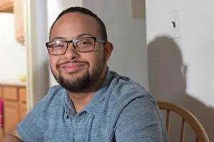 Disorder Prints: Portrait of happy African American man with Down Syndrome at home
