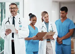 Doctors Prints: Portrait of a happy leader in a group of doctors and nurses planning surgery at the hospital