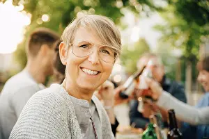 Communications Prints: Portrait of happy mature female sitting with friends at social gathering