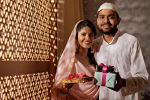 Occasion Prints: Portrait of happy Muslim couple with gift and rose petals on during Eid-Ul-Fitr