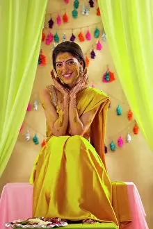 Occasion Prints: Portrait of an Indian bride sitting on stage and posing in front of camera on haldi ceremony