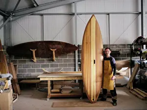 Artisan Prints: Portrait of man holding hand made wooden paddleboard in workshop