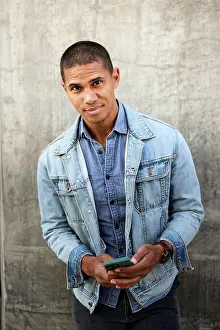 Los Angeles Prints: Portrait of man with smart phone standing against wall